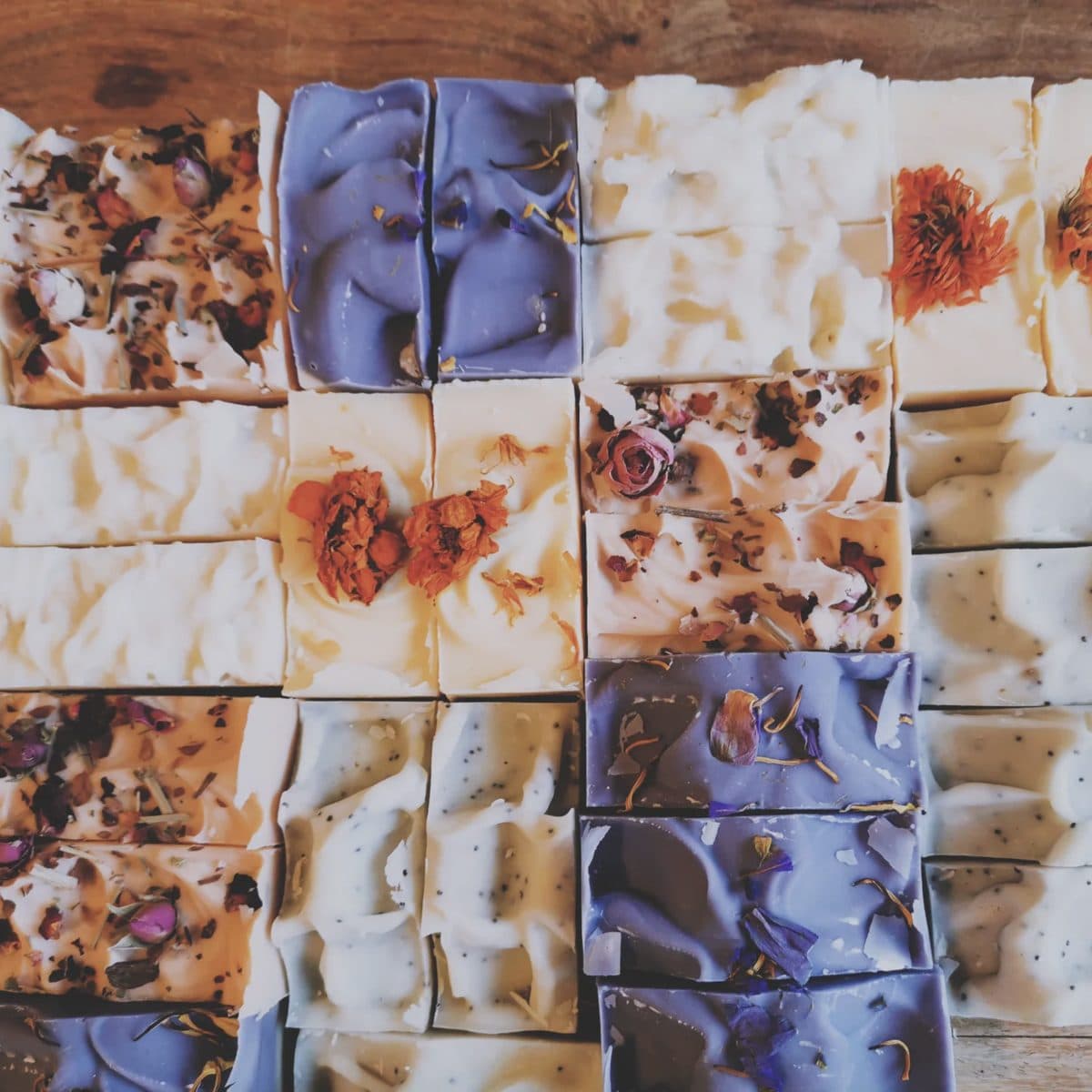 Top-down grid of small-batch botanical soaps, each topped with a different dried flower