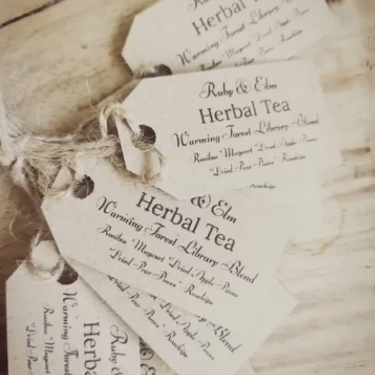 Hand-printed Ruby & Elm Herbal Tea kraft tags, stacked on linen