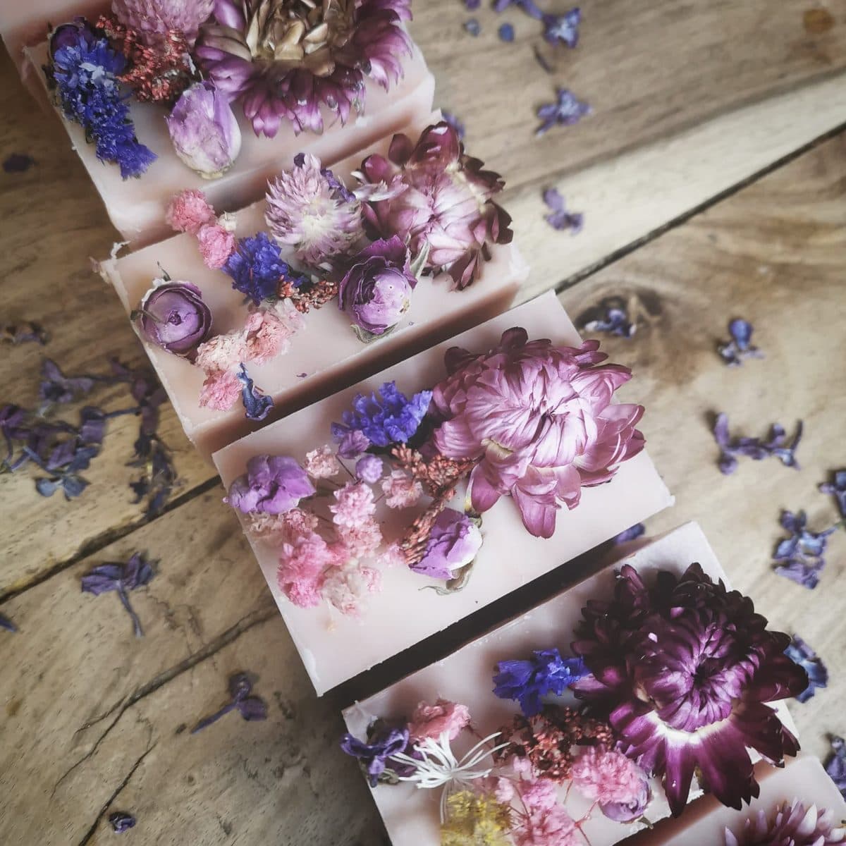 Row of blush-pink artisan soaps crowned with strawflowers and dried botanicals